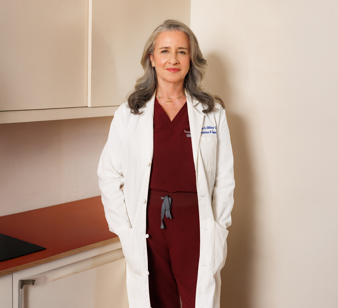 Dr. Suzanne Gilberg wearing a white coat in her medical practice